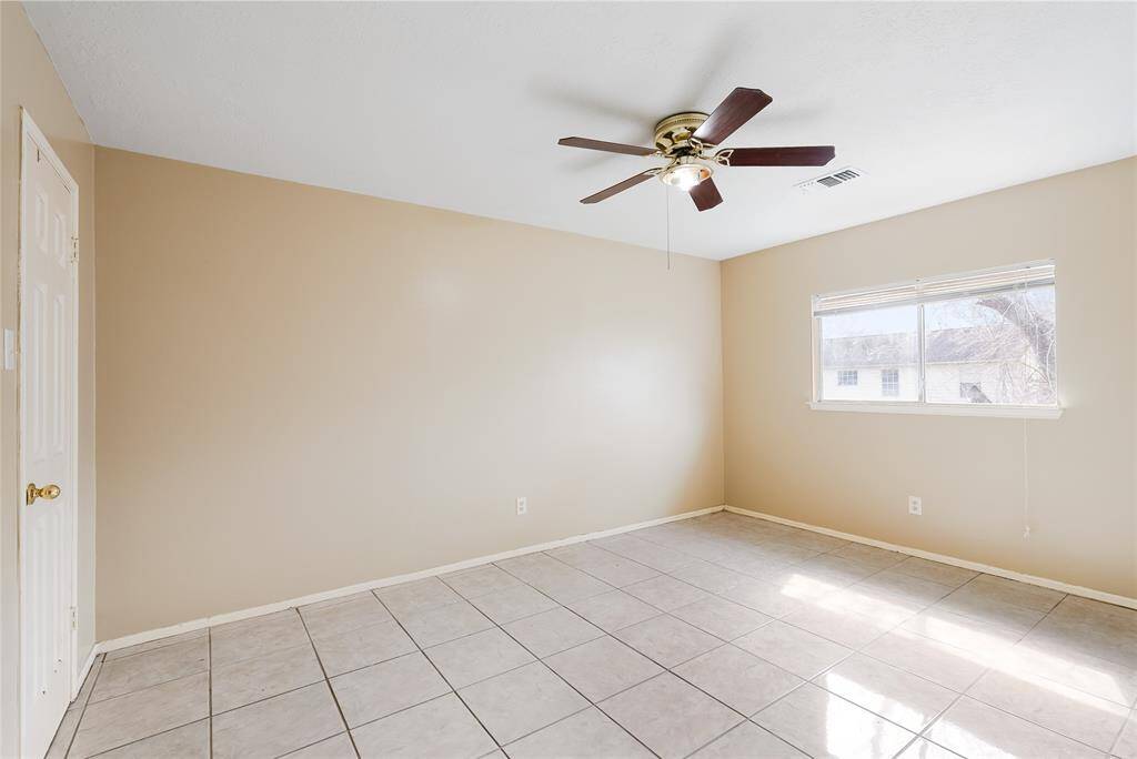 This room features neutral-colored walls and tiled flooring, with a ceiling fan for comfort. A window lets in natural light, creating a bright and welcoming space.
