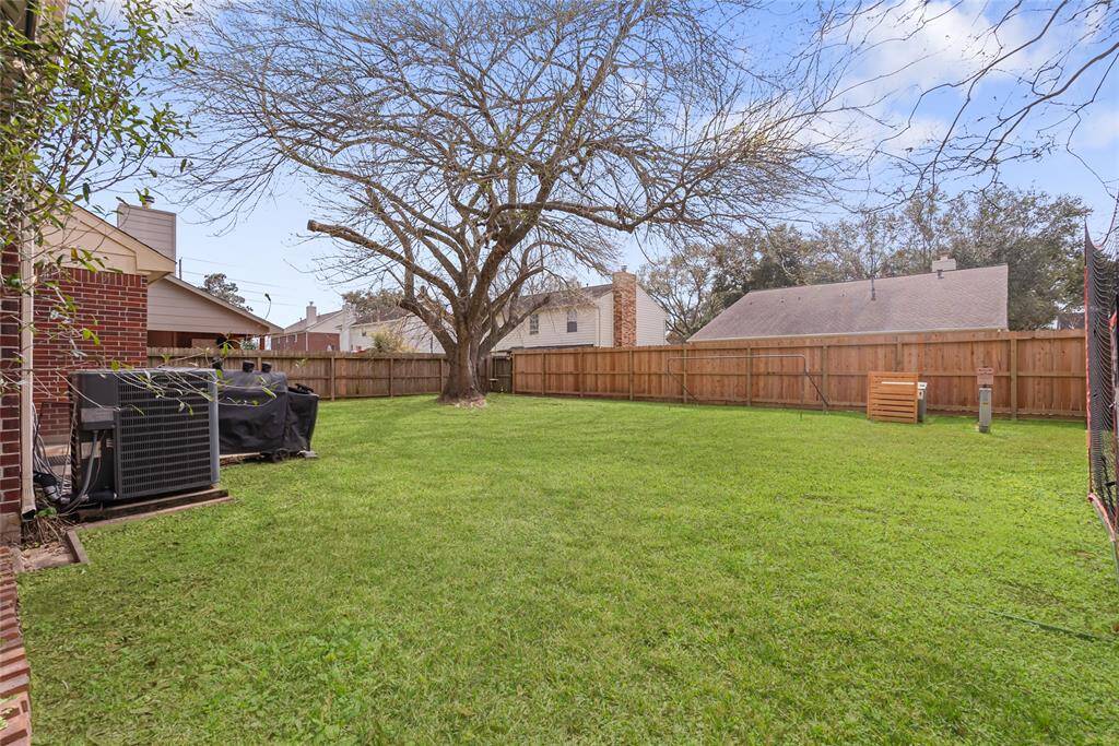 The photo showcases a spacious backyard with a well-maintained lawn, a large tree, and a wooden privacy fence. It's an inviting space for outdoor activities and relaxation.