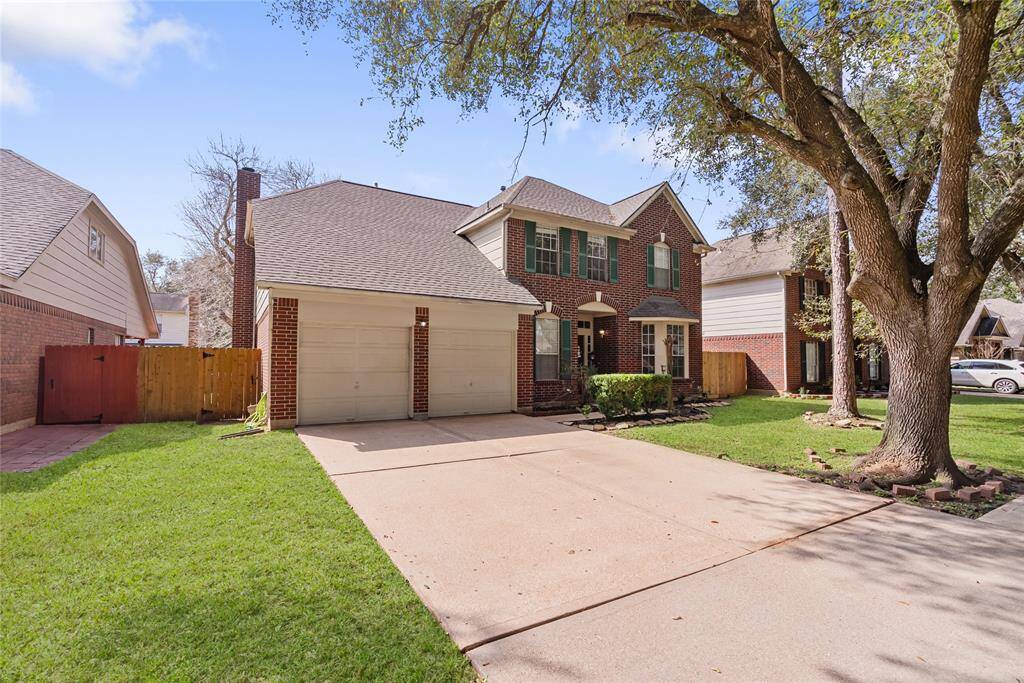 Charming two-story brick home with a well-maintained front yard and mature trees. Features include a two-car garage, inviting entryway, and attractive green shutters. Ideal for family living in a friendly neighborhood.
