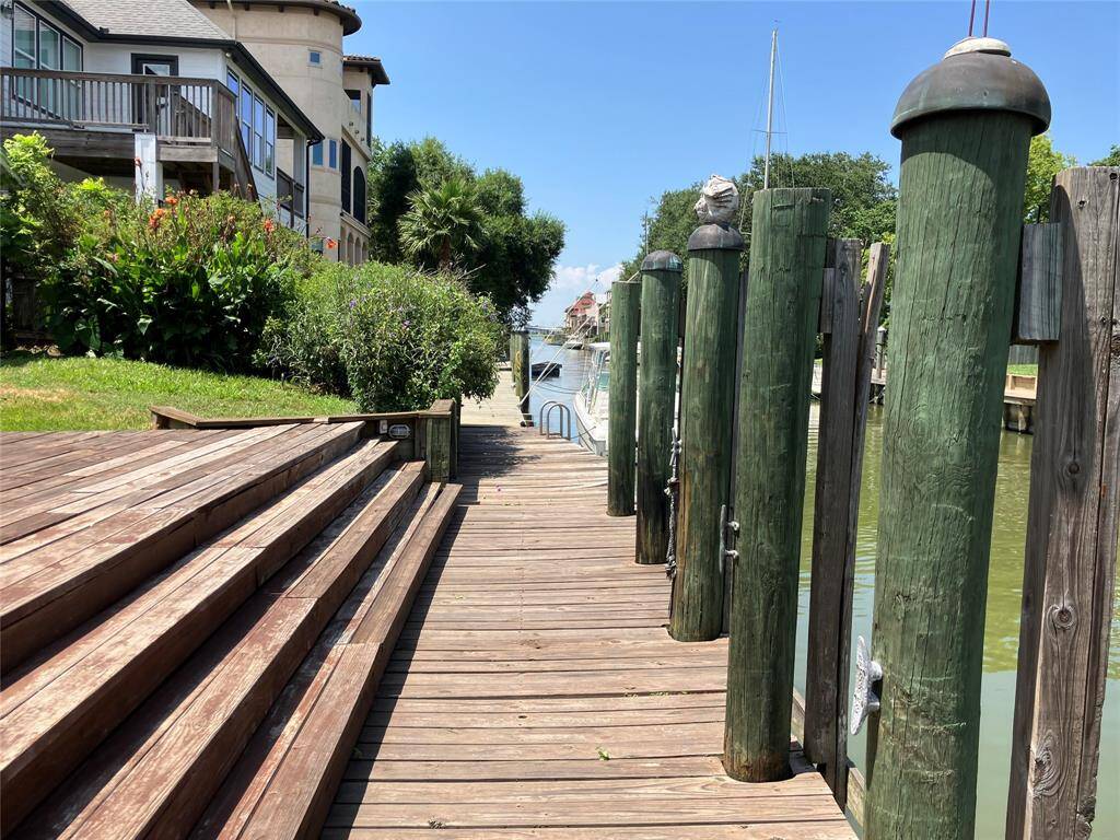 This photo showcases a charming waterfront property with a wooden dock, surrounded by lush greenery and adjacent homes. Ideal for those seeking a serene, picturesque setting with direct water access.