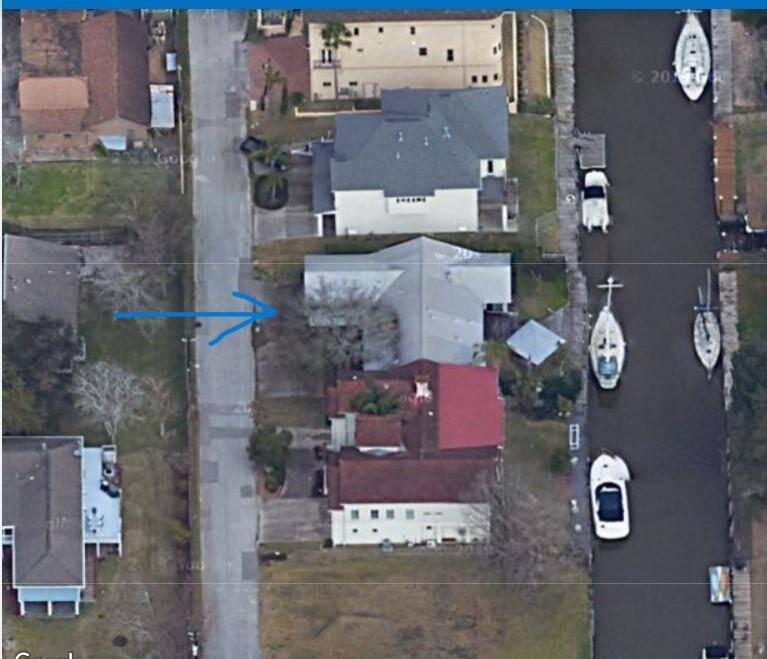 This aerial photo shows a residential area with homes along a canal, where boats are docked. The property of interest is indicated by an arrow, located near the street and waterway, offering waterfront access.