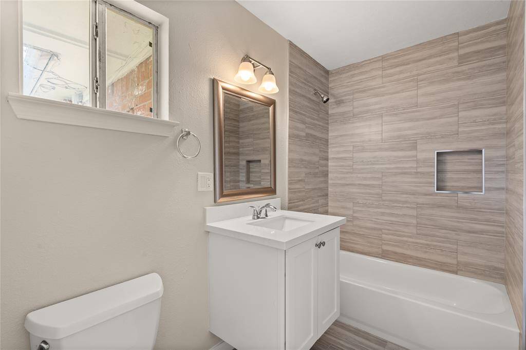 This private bath features tile flooring, bath/shower combo with tile surround, white wood cabinets, beautiful light countertops, mirror, sleek fixtures and modern finishes with direct access to the secondary bedroom.