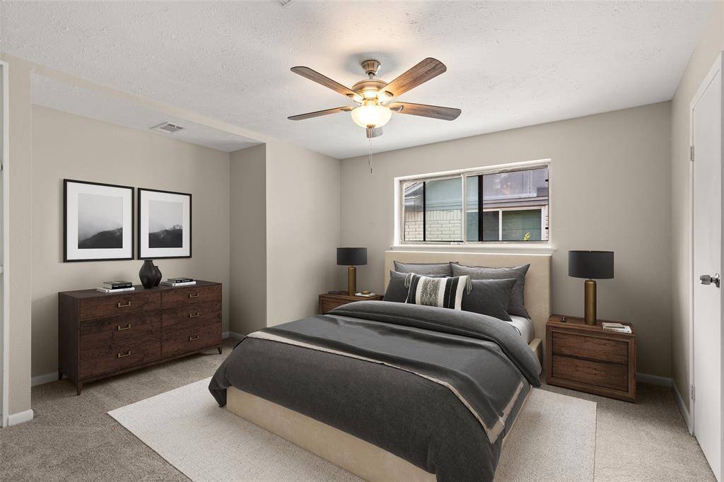 Secondary bedroom features plush carpet, custom paint, dark stained ceiling fan with lighting and a large window.