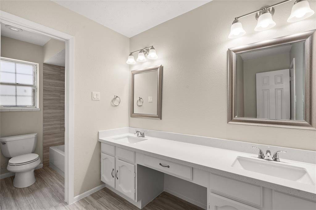 Secondary bathroom features light countertops and cabinets, custom paint, shower/tub combo with tile surround, large mirrors, tile floors, sleek fixtures and modern finishes, plenty of space to accommodate any visiting family or guests.