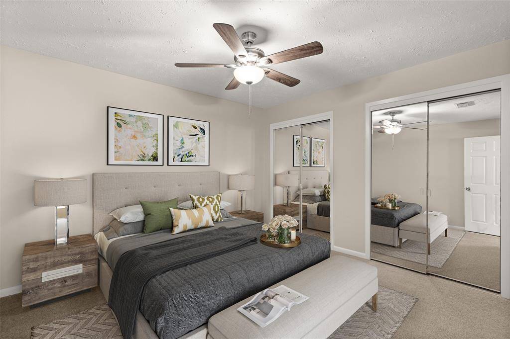 Secondary bedroom features plush carpet, custom paint, dark stained ceiling fan with lighting and a large window.
