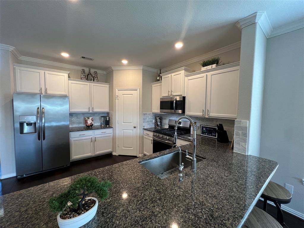 The gourmet kitchen includes a statement island and boasts stainless appliance package, luxury cabinetry, recessed lighting, and direct access to all living areas.
