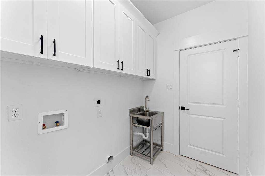 This photo shows a spacious, walk-in closet with multiple wooden hanging rods and white shelving, perfect for organizing clothes and accessories. The space is bright and has a clean, modern look with light wood flooring.