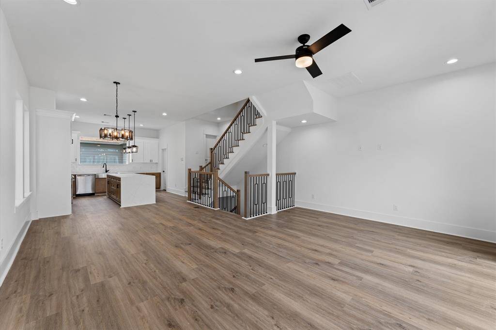 This home features an open-concept living area with sleek LVP floors, a modern kitchen with a central island and stylish lighting, and a contemporary staircase leading to the upper floor. The space is bright and inviting, ideal for entertaining and family living.