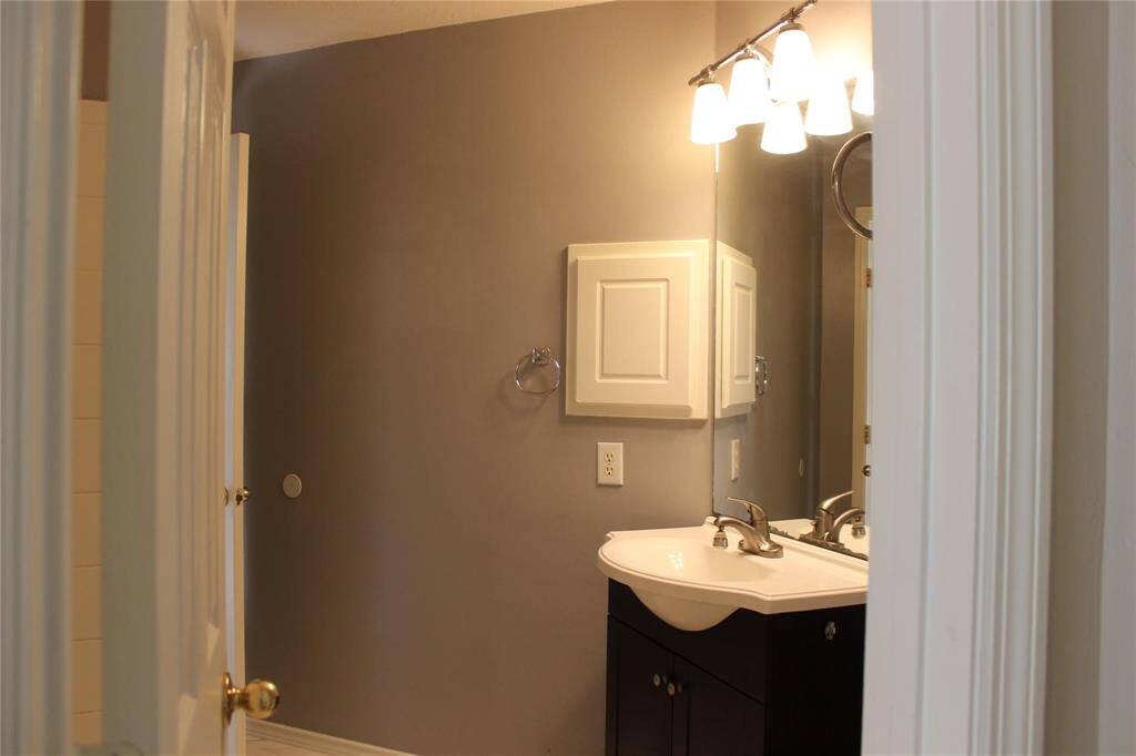 Cozy bathroom with a modern vanity, wall-mounted cabinet, and soft lighting. Neutral gray walls create a calming atmosphere.
