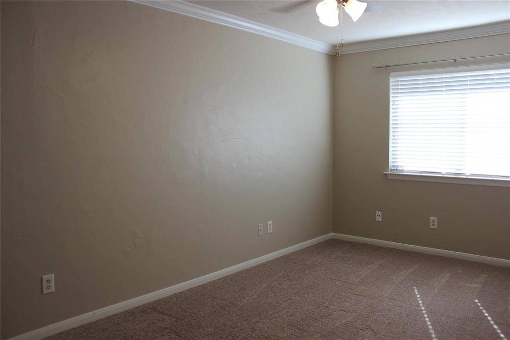This second bedroom is a cozy, carpeted room with neutral walls, featuring a window with blinds that let in natural light. It has a ceiling fan and multiple electrical outlets, making it versatile for various uses.