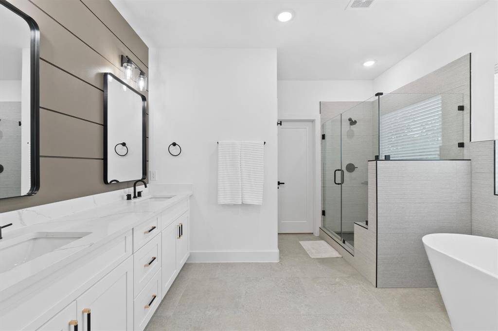 Primary bath with double sinks, soaking tub and walk-in shower with bench seating. Private water closet.