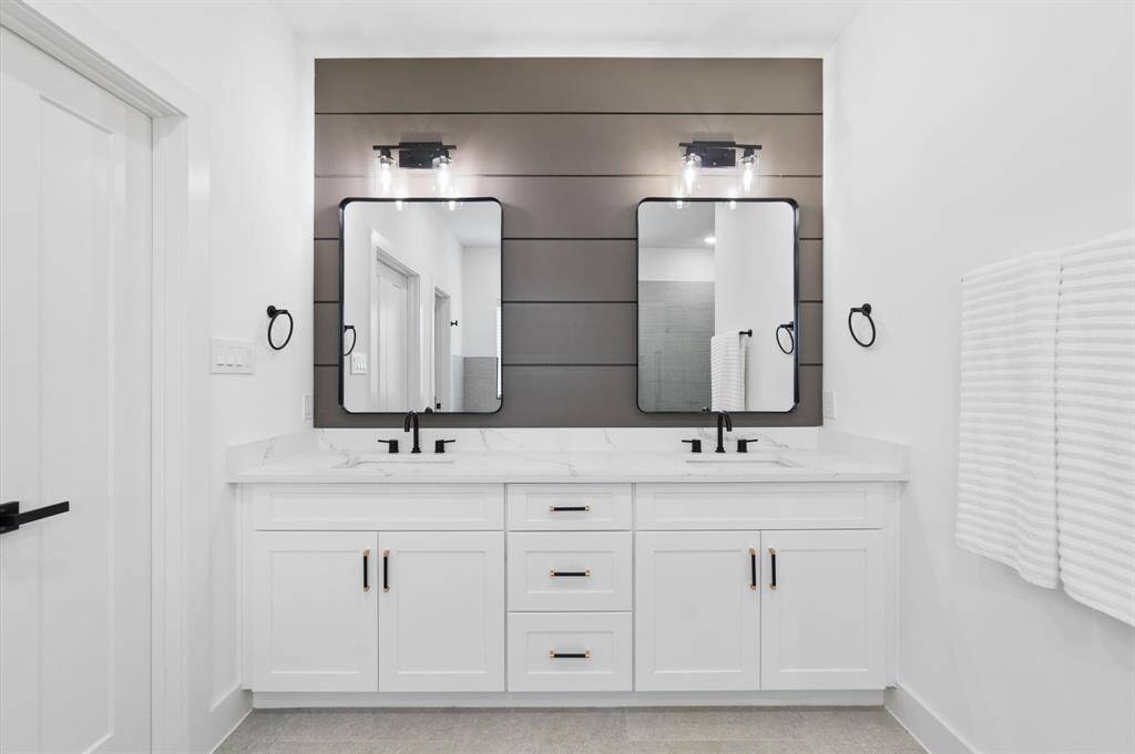 Double sinks vanity featuring stylish lights fixtures and faucets.