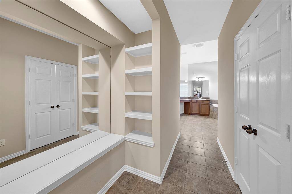The primary bedroom offers an ensuite bathroom with bonus seating, and shelving.