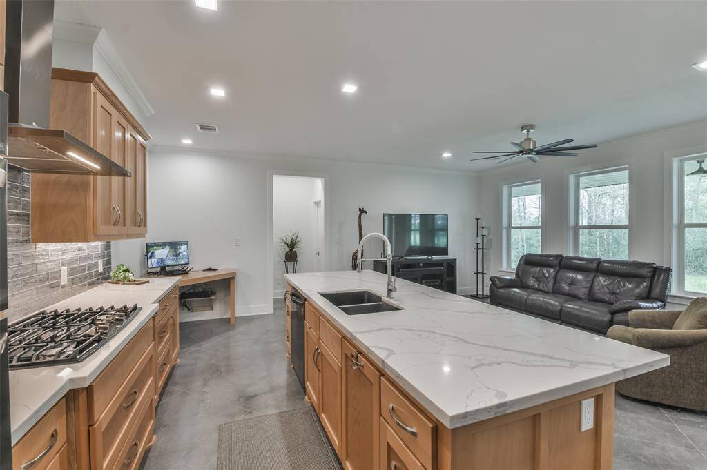 Designer elements throughout including Callacutta Jubilee Quartz countertops, glass tile backsplash, Benchwood shaker-style cabinetry, black stainless appliances, and a spacious island with breakfast bar