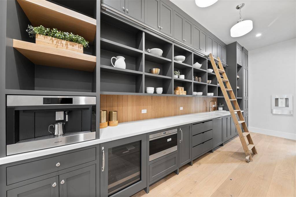 This custom-built luxury butler's pantry combines functionality with refined elegance. Designed with ample storage, it features floor-to-ceiling cabinetry that provides generous space for organizing kitchen essentials and fine diningware.