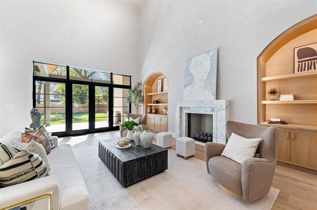 Majestic black custom wood-paneled French doors provide an impressive architectural feature, framing the room with an understated yet bold elegance.