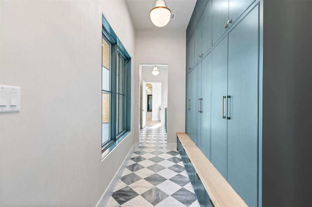 This luxury mudroom offers a perfect blend of style and functionality. The space is anchored by stunning designer tile, which adds texture and visual interest while being durable and easy to maintain. Custom built-in cabinetry provides ample storage for shoes, coats, and accessories, with thoughtfully integrated charging stations to keep devices powered and organized. A full-size washer and dryer are neatly tucked away, making this mudroom as practical as it is beautiful.