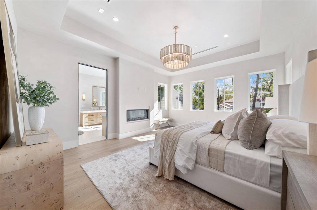 This luxury primary suite is the epitome of relaxation and elegance. A beautiful fireplace serves as the room’s focal point, creating a cozy and inviting ambiance, perfect for unwinding after a long day. The tray ceiling adds an extra layer of sophistication, enhancing the sense of space and adding architectural depth.