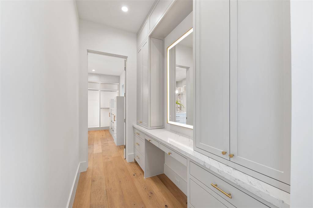 On the way to the stunning walk-in closet the primary suite features the custom built in vanity area with lit makeup mirror.