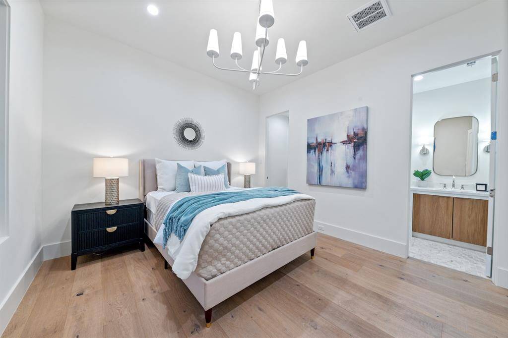 This stunning secondary bedroom offers a serene retreat with its airy, light-filled ambiance. The elegant white oak floors add warmth and sophistication, while grand windows invite in natural light and picturesque views. A statement designer light fixture enhances the room’s modern luxury, making it a perfect blend of comfort and style. With generous space for furnishings and personal touches, this bedroom is a true haven of relaxation.