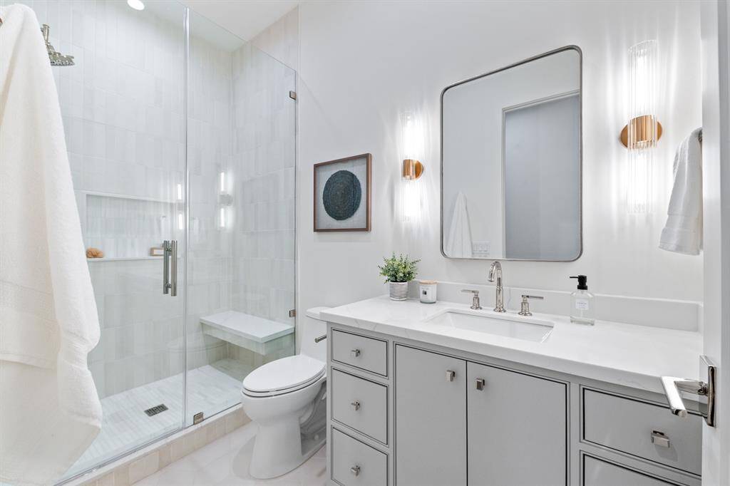 Step into a sanctuary of modern elegance in this beautifully designed secondary bathroom. Crisp finishes and high-end tilework create a bright and airy ambiance, elevating the space with timeless charm. The walk-in shower, adorned with intricate tile detailing, serves as a stunning focal point, while the sleek vanity provides ample storage and refined style. Perfectly curated for luxury and relaxation, this bathroom is a true masterpiece.