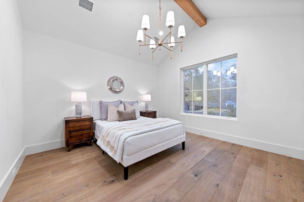 Spacious and refined, this secondary bedroom is designed with both beauty and functionality in mind. The rich white oak flooring complements the soft, neutral palette, creating a cozy yet upscale atmosphere. Expansive windows bathe the room in natural light, highlighting the exquisite designer lighting overhead. With ample space to accommodate a sitting area or custom furnishings, this bedroom offers the perfect blend of luxury and comfort.