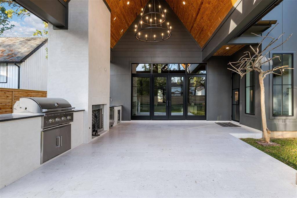 This luxury patio kitchen seamlessly blends outdoor living with sophisticated design. A spacious built-in grill and sink make this space ideal for entertaining, while a massive fireplace adds both warmth and ambiance, perfect for cooler evenings.