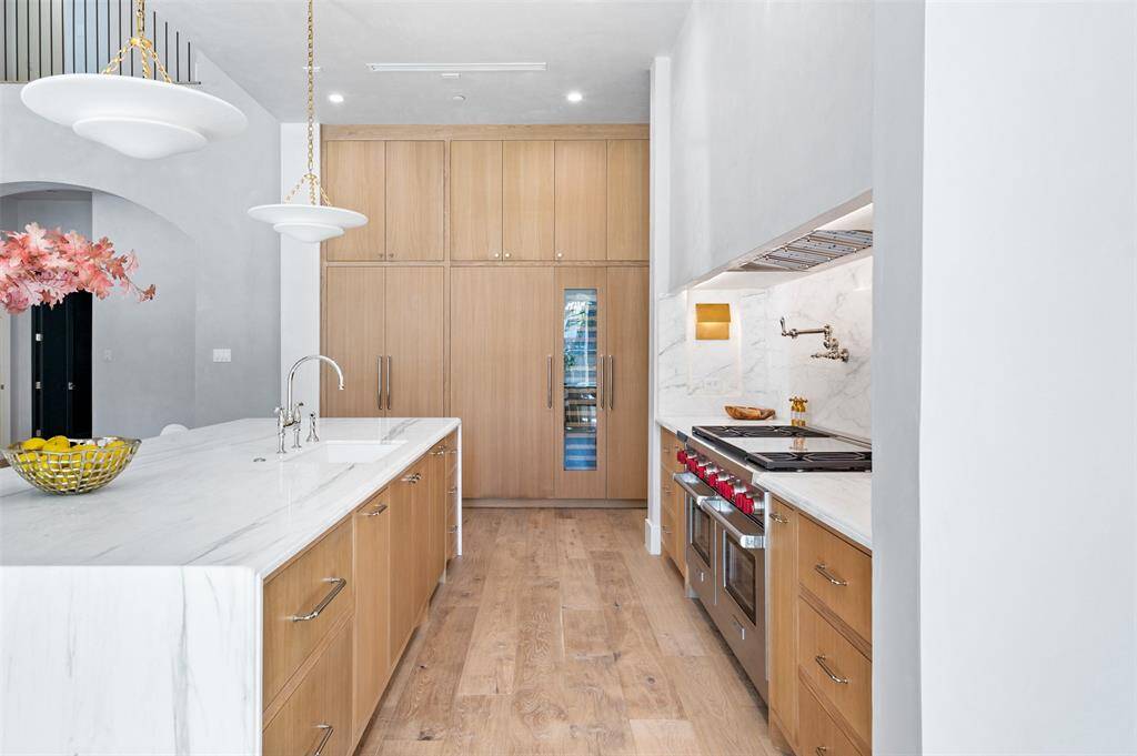 Designer lighting hangs above, casting a soft glow and accentuating the kitchen's high-end finishes.