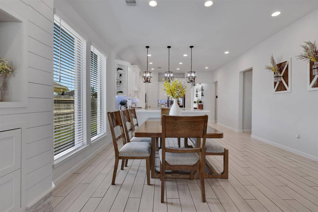 This photo showcases a bright, open dining area. Large windows provide ample natural light. The space seamlessly connects to the kitchen, enhancing the open-concept design.