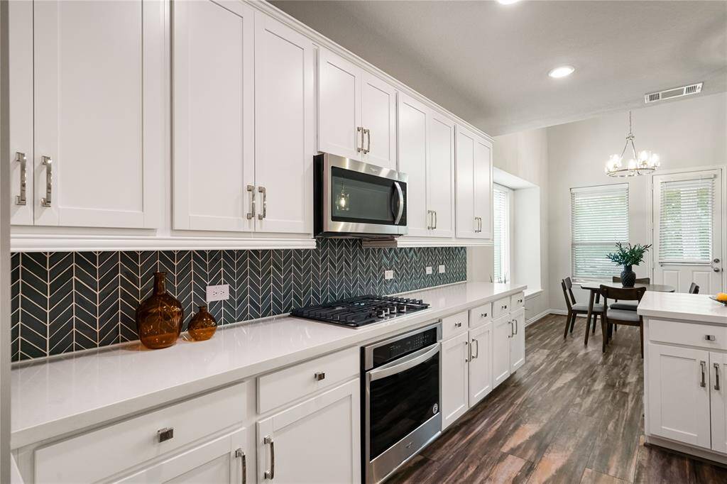 Upgraded cabinets, hardware, countertops, backsplash, flooring, appliances, and lighting
