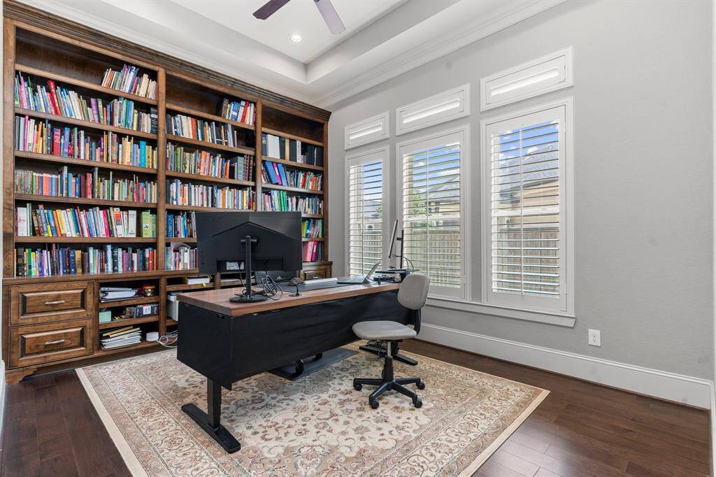 This home office is a true standout, featuring impressive tall, coffered ceilings, a custom-built bookshelf, beautiful wood floors, and so much more!  Beautiful Plantation Shutters!