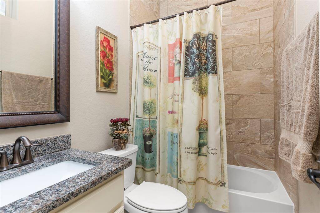 The downstairs guest bathroom boasts beautiful granite countertops, a deep undermount sink, a framed mirror, and a tub-and-shower combination with upgraded tile surround—perfectly designed for both style and function!