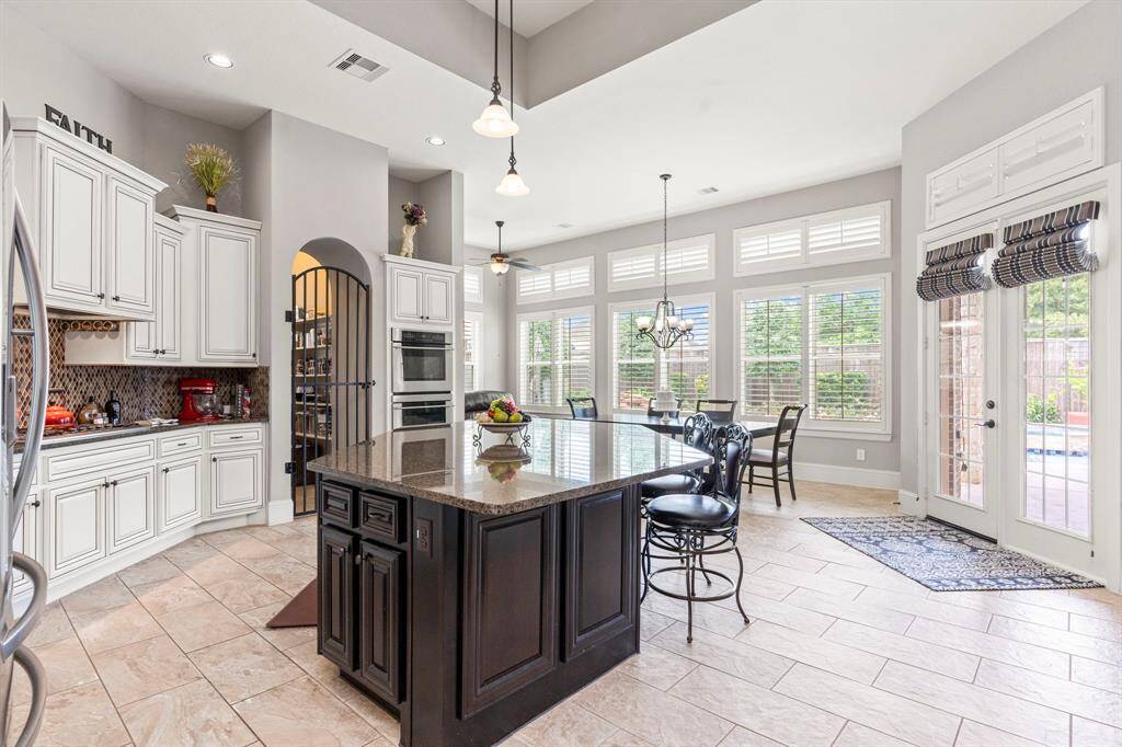 Wow! The huge walk-in pantry features a stunning custom iron door, adding a touch of elegance. Walls of windows provide beautiful views of your backyard oasis, while tall French glass doors open to your inviting covered patio—perfect for indoor-outdoor living!