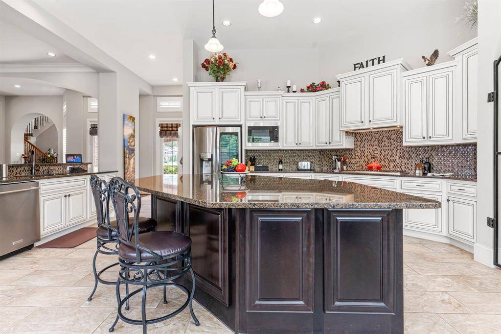 The family area features soaring high ceilings, beautifully trimmed with crown molding. A stunning large cast stone fireplace sets the perfect stage for holiday gatherings. Down a private hallway, you'll discover the secluded primary suite—your own peaceful retreat.  Look at all the custom crown molding!