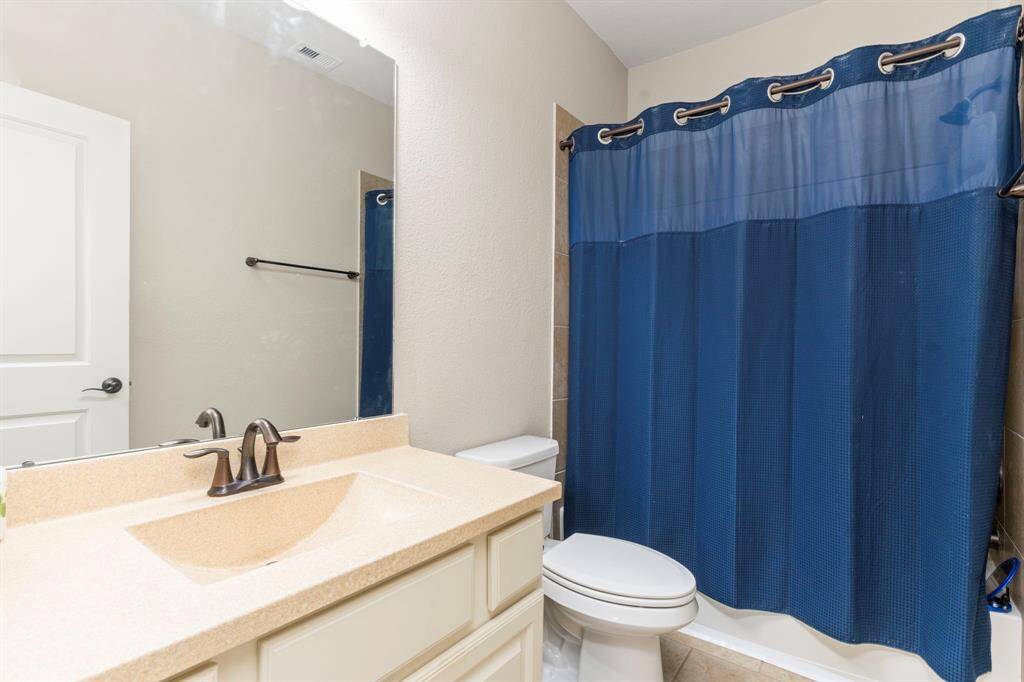 The private en-suite bathroom features an upgraded smooth surface countertop, along with a tub-and-shower combination, offering both style and convenience.