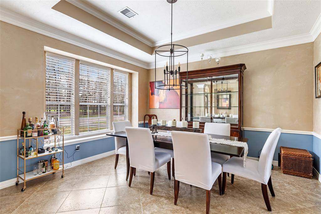 Very nice formal dining room with raised ceiling, updated lighting fixture and triple windows providing natural lighting. Tile flooring for easy clean up.