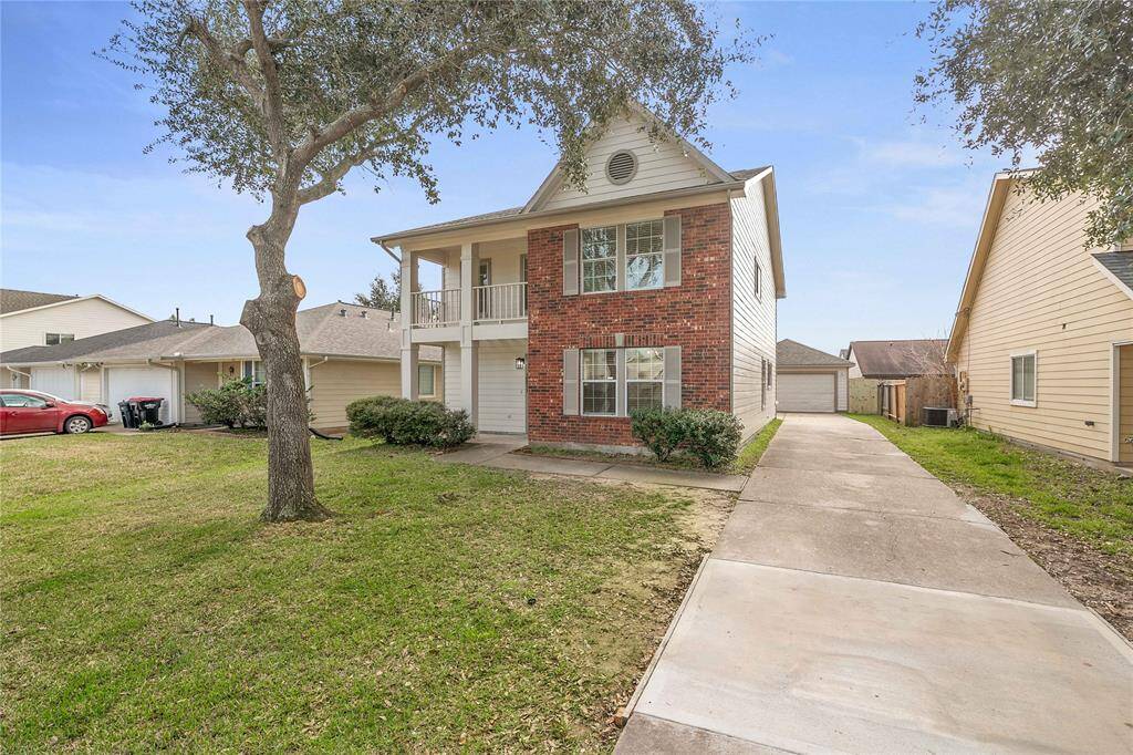 This two-story home features a brick and siding facade, a spacious driveway, and a covered front porch. It has a well-maintained lawn with a mature tree, offering great curb appeal in a suburban setting.