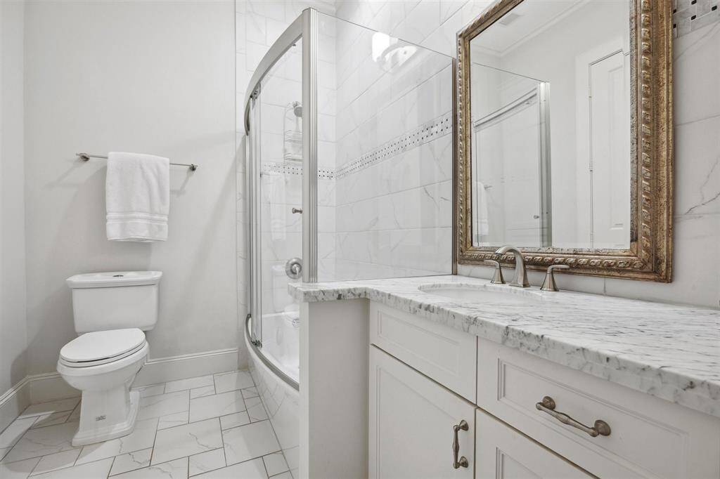 Secondary bathroom incudes marble countertops and sleek porcelain tiles.