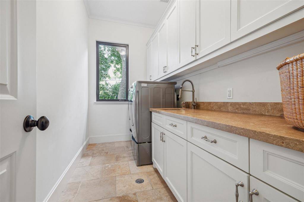 The sunlit laundry room features sleek cabinetry and a handy utility sink.