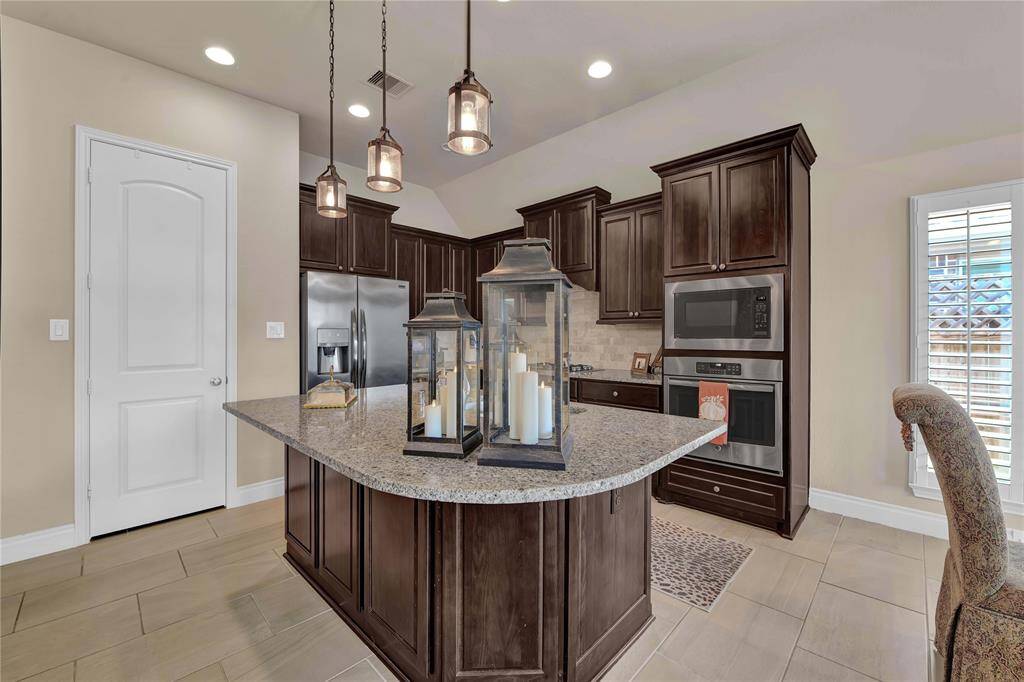 Stylish pendant lighting hangs overhead, adding a contemporary flair and illuminating the area, making it perfect for gatherings or early morning coffee. Equipped with top-of-the-line stainless steel appliances, this kitchen is a chef's dream.