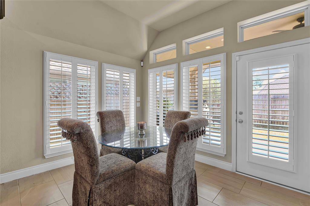Adjoined to the stunning kitchen is a bright & spacious breakfast room, where large windows with plantation shutters create a cheerful atmosphere filled with natural light. A door leads directly to the oversized covered patio, seamlessly blending indoor & outdoor living. The sleek tile flooring continues into the breakfast room.