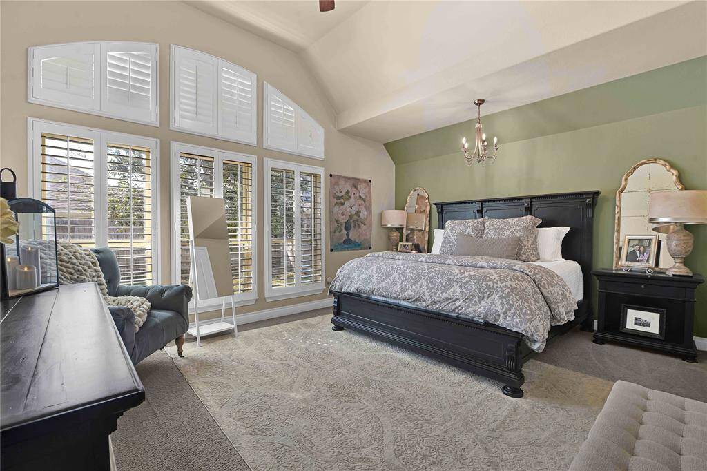 In this private sanctuary, the primary bedroom provides the perfect space for relaxation and rejuvenation. Plush carpet underfoot adds a soft, inviting touch, while soaring vaulted ceilings overhead create an airy, expansive feel.