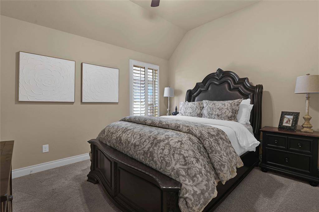This spacious second secondary bedroom also offers ample room. A large window with plantation shutters allows natural light to flow in while maintaining privacy. The plush carpet underfoot adds warmth, & the high ceiling with a ceiling fan enhances the room’s airy feel. A generous walk-in closet provides plenty of storage.