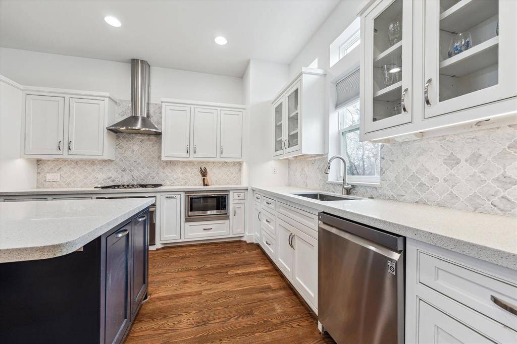 All stainless steel appliances in this clean and pristine kitchen. Lovely inset cabinets with hidden hinges, a window over the sink, and glass front cabinets.