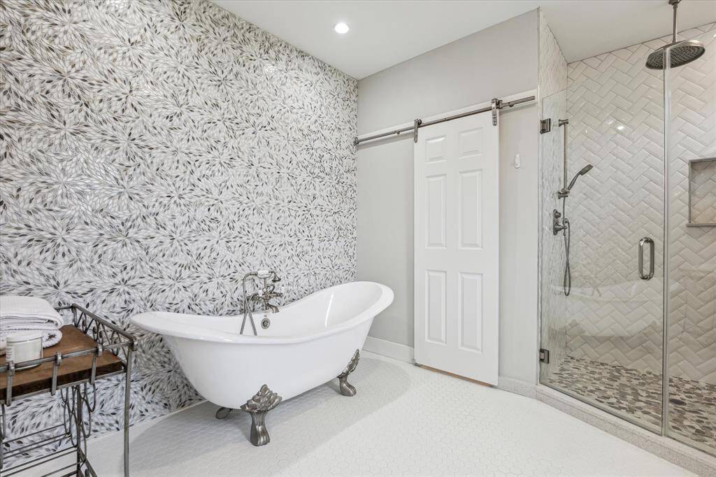 The freestanding clawfoot tub serves as a breathtaking focal point, inviting you to unwind in style. Complementing the tub is a fully tiled accent wall, adding depth and texture with its exquisite design.
