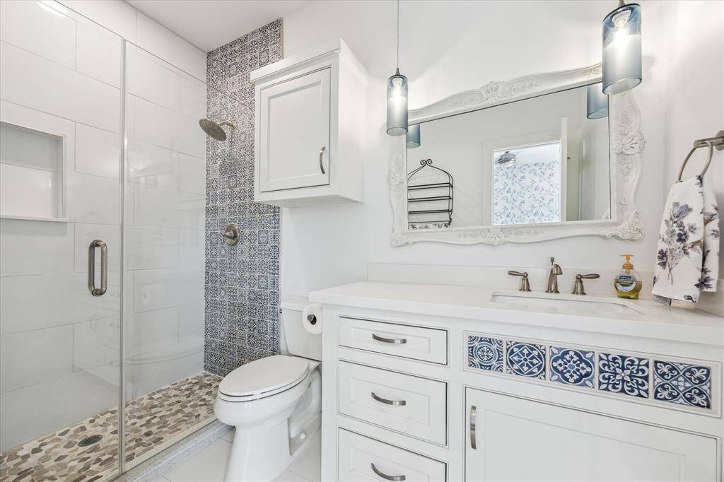 This stylish en-suite bathroom offers a spa-like experience with a walk-in shower featuring custom tilework that adds a touch of luxury and personality. The thoughtfully designed layout provides privacy and convenience, making it the perfect complement to the third-floor guest suite. A sleek vanity with ample storage and elegant finishes completes the space, ensuring both functionality and sophistication.
