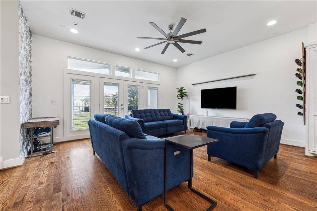 The living room features a wall of windows with a walk-out balcony and views of downtown Houston. The double doors allow for fresh air and plenty of natural light.