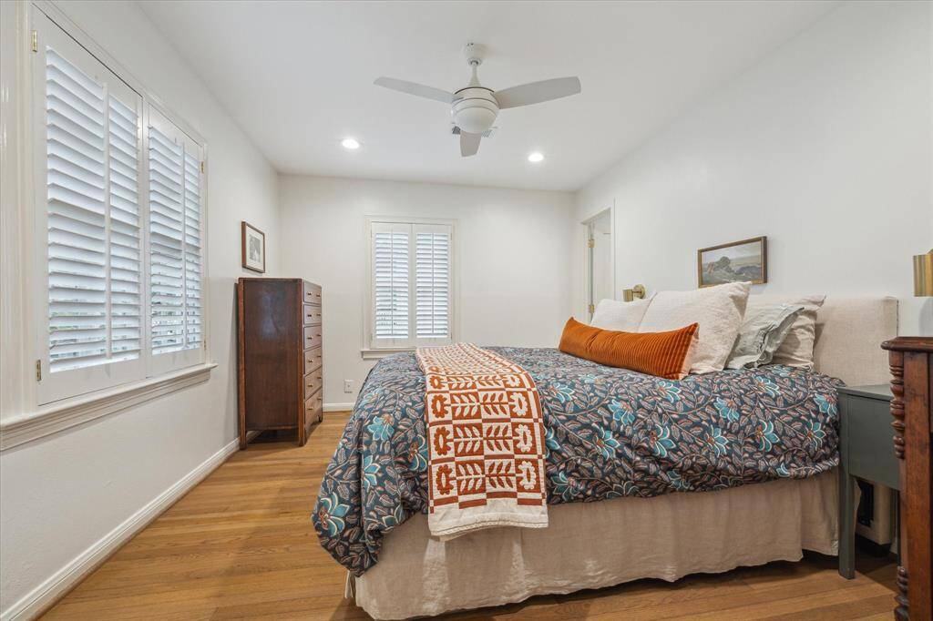 Primary bedroom with ensuite bath, hardwood floors, windows overlooking front and side yards, recessed lighting and fan lighting.