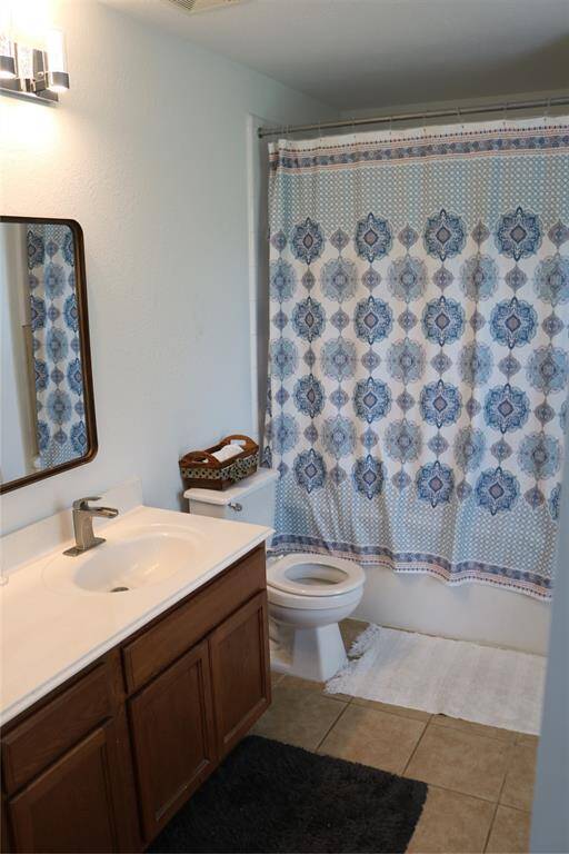 Spacious primary bathroom features caramel-colored cabinets, large mirror, undermount sink and shower-tub.
