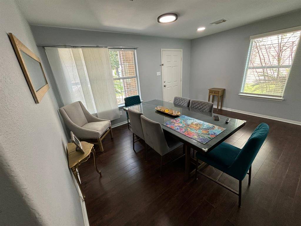 This elegant dining room, bathed in natural light from its large windows, offers a warm and inviting atmosphere, perfect for family gatherings or intimate dinners. The hardwood floors add a touch of sophistication, making this space ideal for creating unforgettable moments.